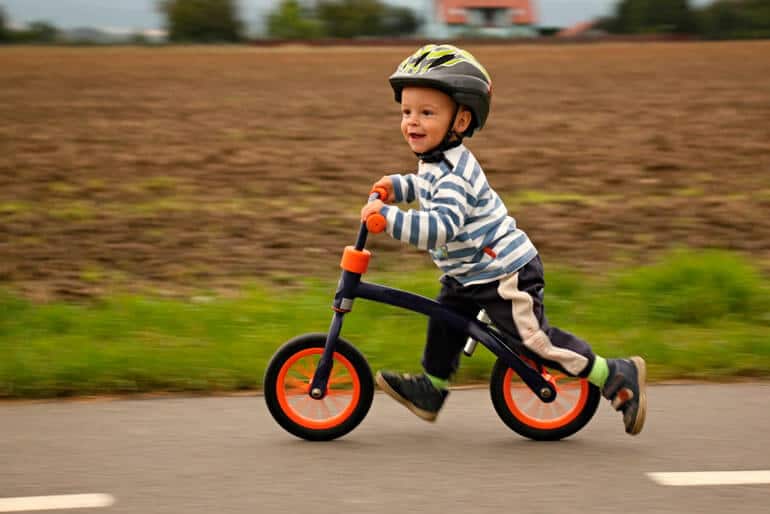 boy in helmet riding orange bike