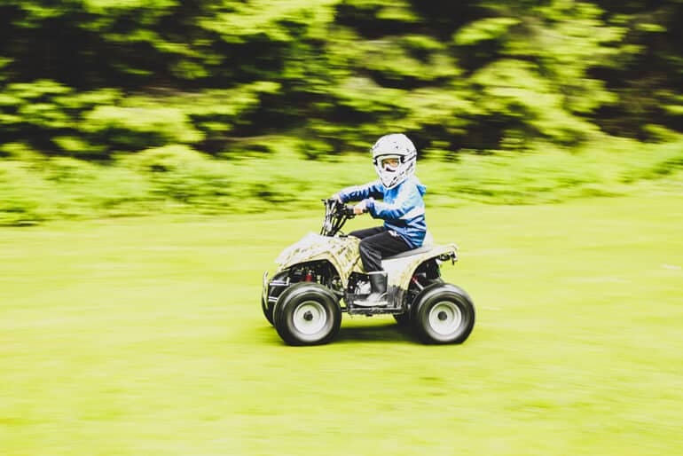 boy is riding a camo ATV