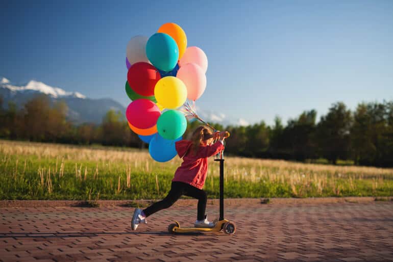 girl with balloons on a scooter