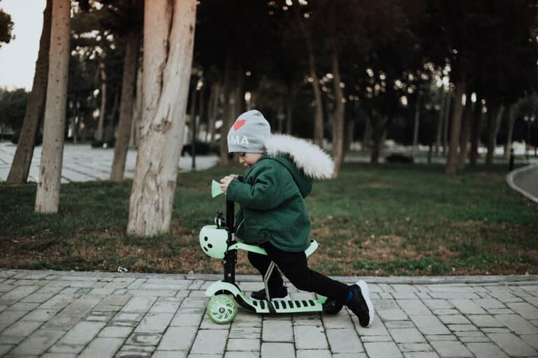little boy is on green scooter