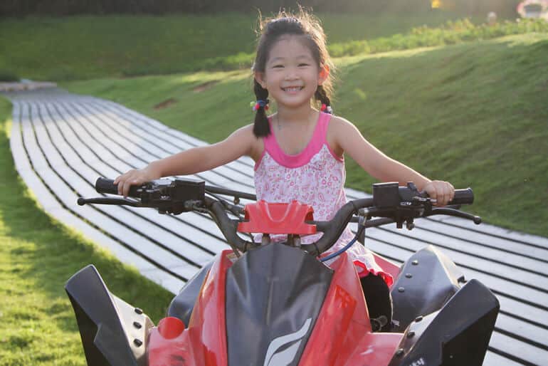 little girl riding red four wheeler